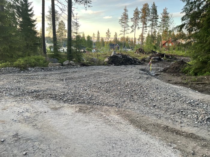 Grusad infartsväg under anläggning med avverkat skogsparti i bakgrunden.