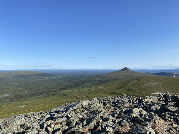 Utsikt från Städjan i Idre med fjäll och blå himmel, synligt kala bergstoppar och gröna dalar.