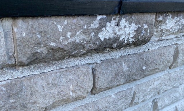 Svårt borttagbara svarta fläckar på tegelvägg trots rengöring, nära fönsterkarm.