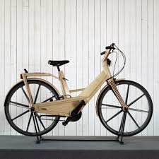 Beige Itera plastcykel parkerad framför en vit vägg.