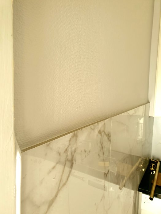 Nyinstallerade granitklinkers i kök med ojämn övre kant vid vägg, synlig silikon saknas.