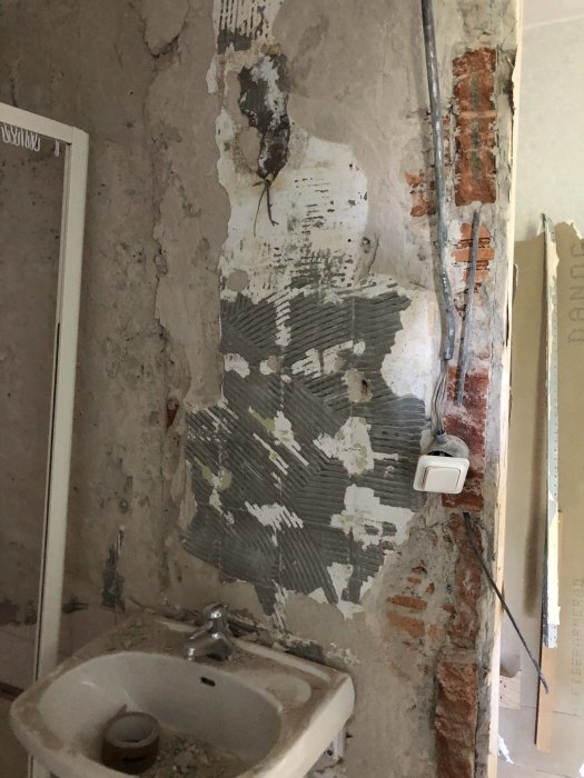 Renoveringsprojekt av badrum med porös puts och synliga slaggplatteblock på väggen, samt handfat.