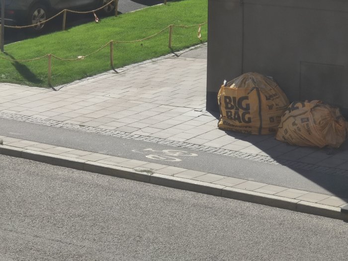 Cykelbana med cykelsymbol på marken och byggsäckar vid sidan av banan.