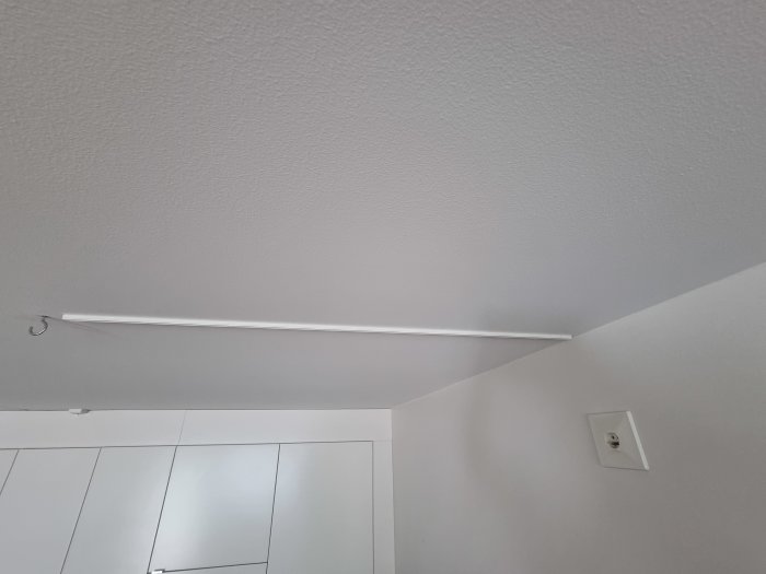 Tak med krok för lampa och närliggande vägguttag i en modern bostad.