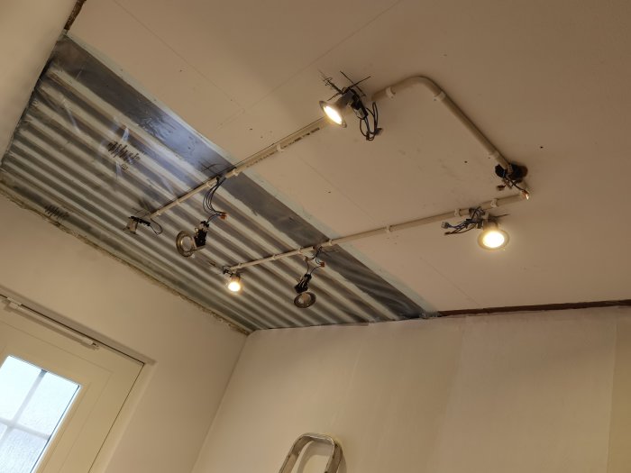 Renoverad halltak med ovanlig belysning monterad på synliga rör och en galvaniserad järnplåt.