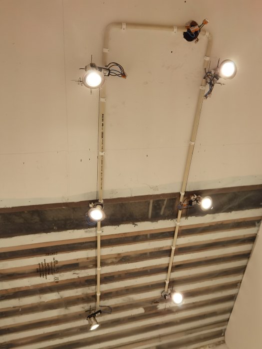 Renoverad halltak med nyinstallerade spotlights och synliga rör och kablar.