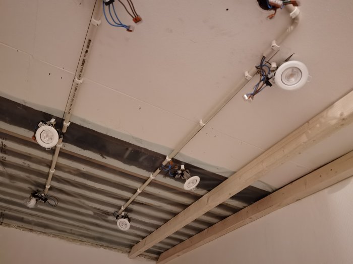 Renoverad halltak med öppen elinstallation och spotlights monterade i ej färdigställt tak.
