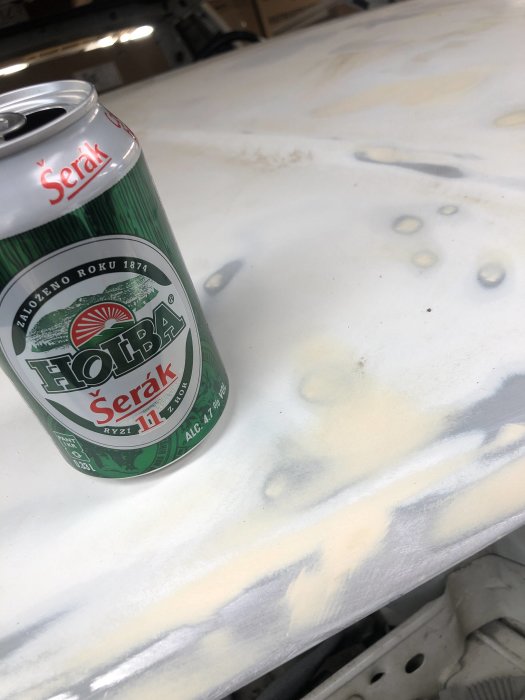 En burk öl på ett slipat bilkarosseri i ett garage.