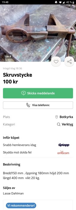 Rostigt skruvstycke i gjutjärn på smutsigt underlag, synlig skruvjustering och gripkäftar.