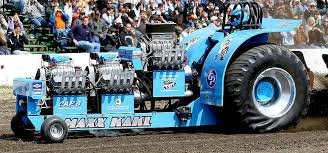Modifierad blå traktor med flera motorer under en tractor pulling-tävling inför publik.