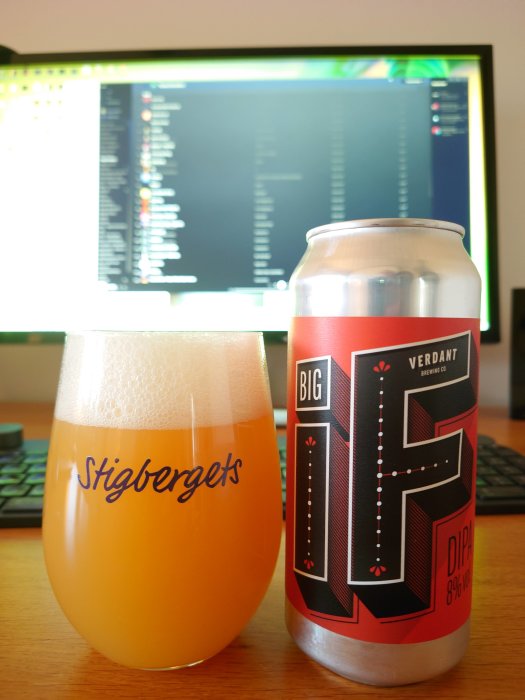 Ett glas med öl märkt "Stigbergets" och en burk av "Big IF" från Verdant framför en datorskärm.
