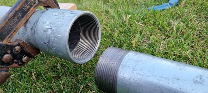 Galvat rör med för kort gänga bredvid öppet rör, gräsmatta i bakgrunden.