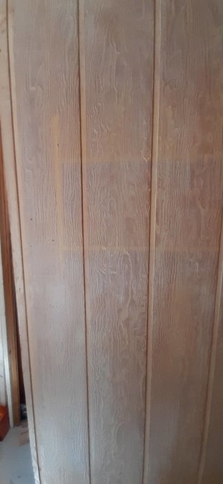 Obehandlade plywoodskivor på en vägg med synlig struktur och flera spikhål redo för spackling och målning.
