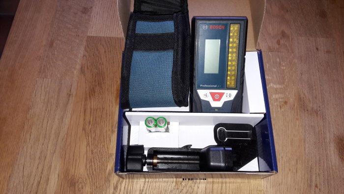 Bosch mottagare för laser med tillbehör i förpackning på trägolv.