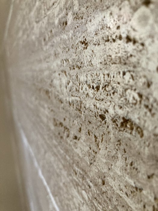 Närbild på en porös och gropig marmorliknande stenvägg.