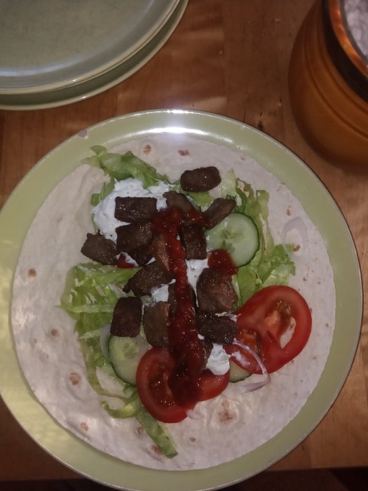 Hemlagad kebab med sallad, rödlök, gurka, tomat och såser på tortilla.
