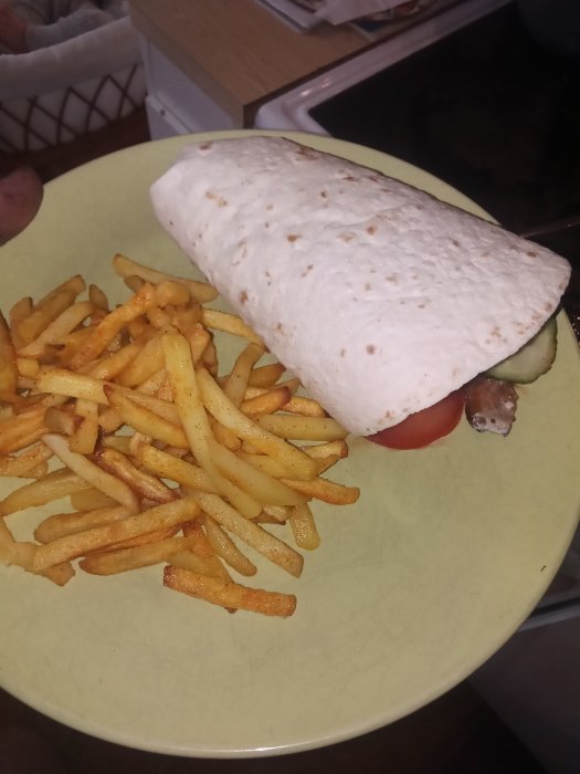 Hemgjord kebab i tortillabröd med pommes frites på en tallrik.