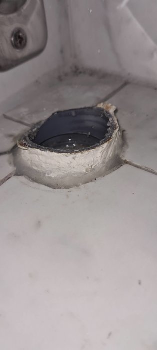 Snett kapat rörstick upp cirka 1 cm från golv med synlig gummimuff och fuktspår.