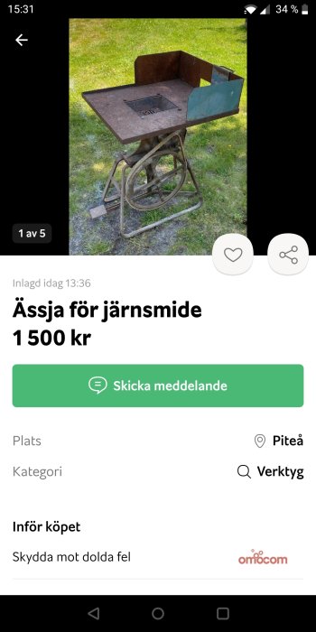 Rostig ässja för järnsmide på ett gammalt trampställ utomhus på gräsmatta.