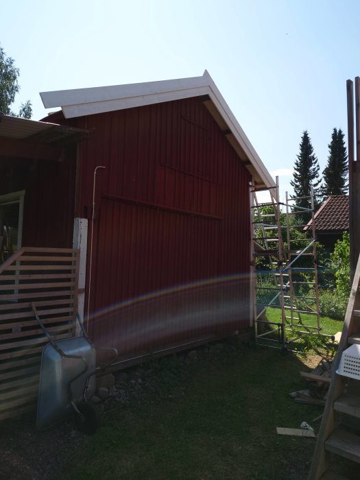 Nyinstallerade vindskivor på rödfärgat garage med stegar och byggmaterial synliga.