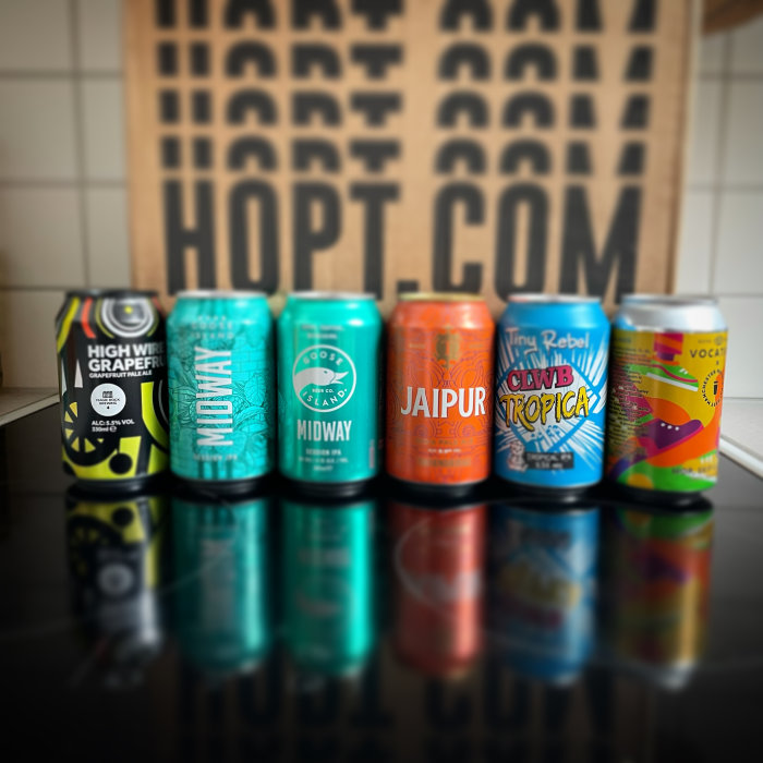 Rad av olika ölburkar mot suddig bakgrund med texten "HOPT.COM