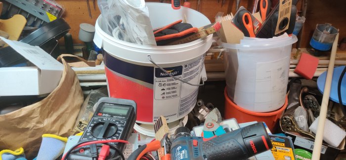 Rörigt arbetsbänk med verktyg och byggmaterial, trolig plats för en förlorad skruv.