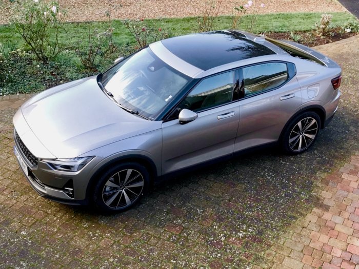 Polestar 2 parkerad på en uppfart med grönskande buskar i bakgrunden.