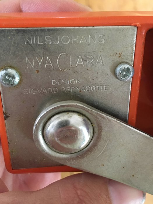 Närbild av en gammal orange konserveringsöppnare 'Nilsjohan Nya Clara', design Sigvard Bernadotte.