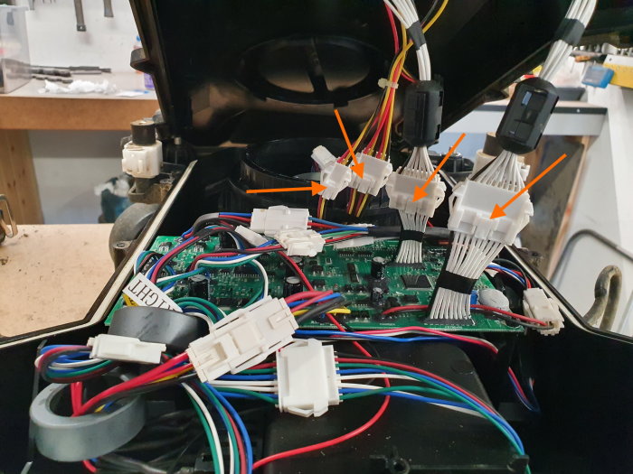 Öppen robotklippare som visar kretskort och kablage, märkt för batteribyte.