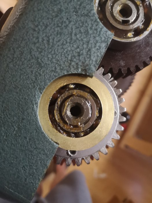 Närbild på ett maskinelement med nytt mässingsshims och täcklocket synligt.