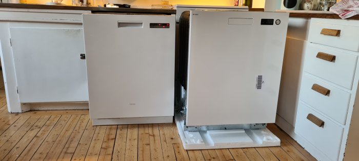 Jämförelse mellan två diskmaskiner, gammal Cylinda till vänster och ny Asko till höger, på ett köksgolv.
