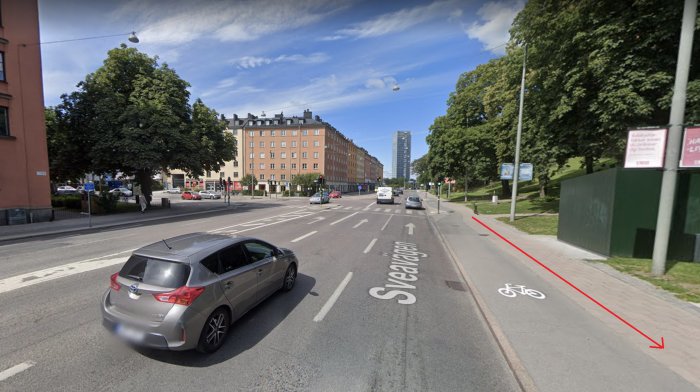 Stadsgata med cykelbana och pil som visar cykelriktning längs med en park.