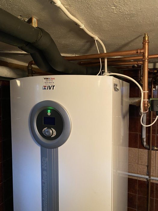 Bergvärmepump i pannrum med synliga kablar och rörinstallationer.
