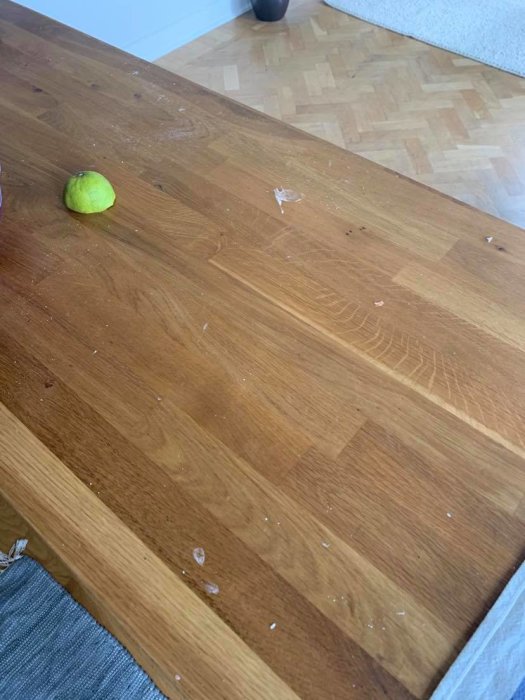 Klibbig träbänkskiva med fastklistrade matrester och en grönlime.