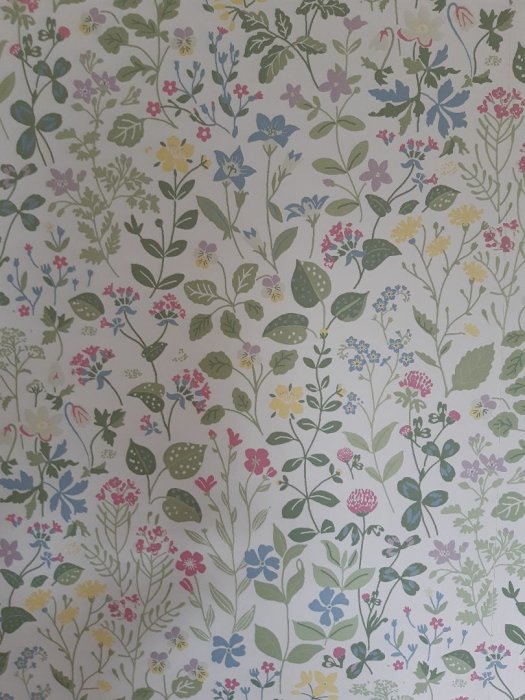 Blommig tapet med olika färgade växter och blommönster på en ljus bakgrund.