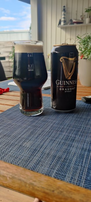 Ett glas mörkt öl och en Guinness burk på ett bord utomhus, avkoppling efter löpning.