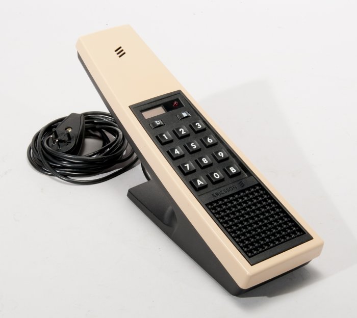 En beige Ericsson snabbtelefon från 80-talet med numeriskt tangentbord och sladd.