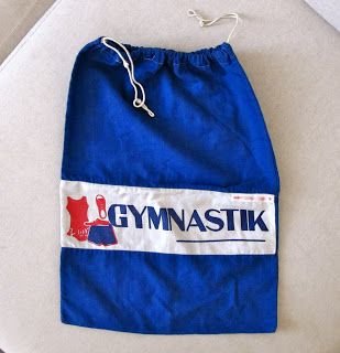 Blå gympapåse med vitt snöre och texten "GYMNASTIK" plus en röd symbol.