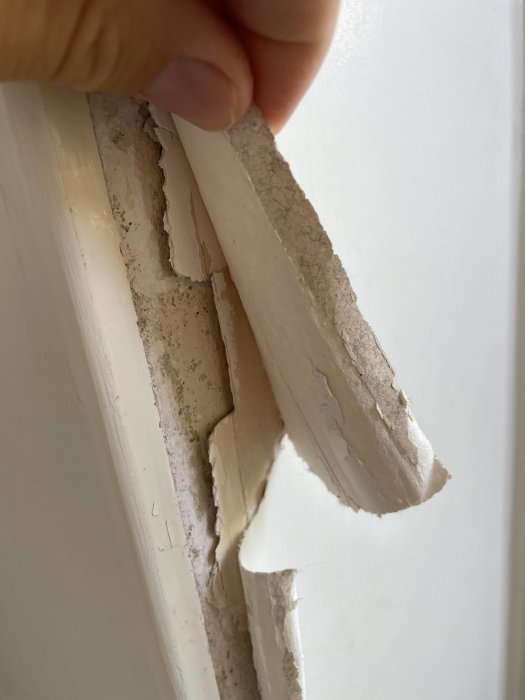 Krullande och sprucken skiva vid fönstersmyg i äldre lägenhet.