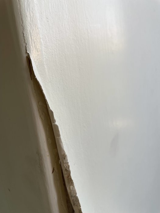 Krullande och sprickande ytskikt vid fönstersmyg i en äldre lägenhet.