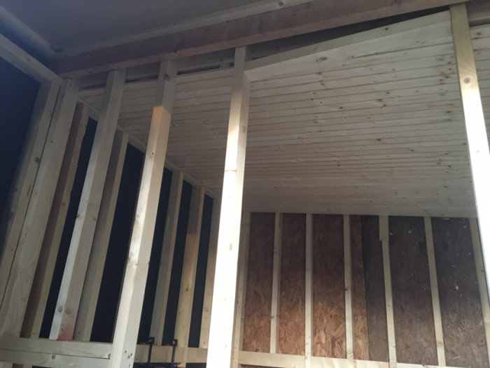 Nybyggd trästomme i ett byggprojekt med isolering i väggarna och tak klätt i träpanel.