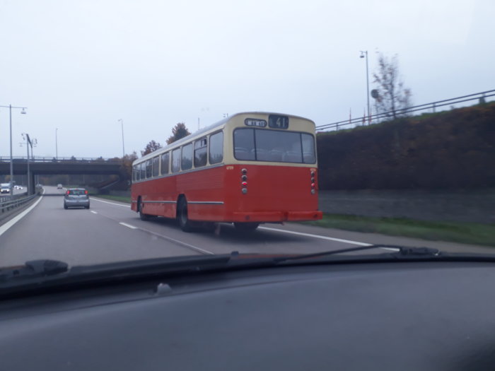 Röd vintagebuss med nummer 41 på vägen sedd från insidan av en bil.