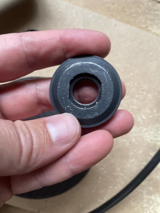 Hand som håller en svart o-ring avsedd för vinkelslip, synlig profil och mittöppning.