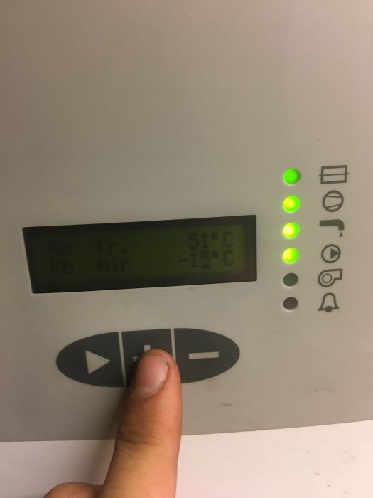 Hand pekar på display av bergvärmepump med felaktiga temperaturvärden.