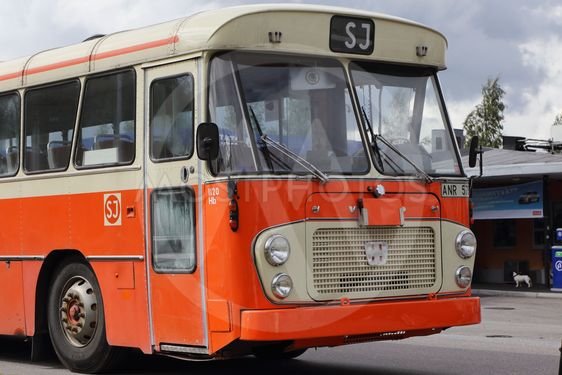 Gammal orange och vit SJ buss med företagets logo parkerad, minne från förr.