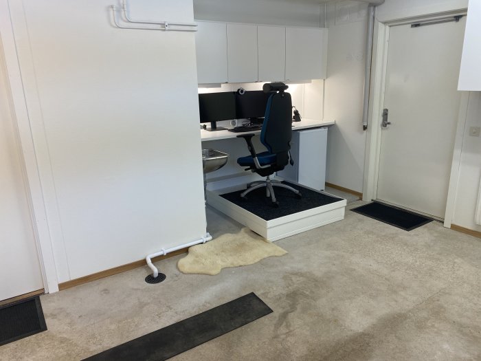 Garage omvandlat till kontorsutrymme med arbetsbänk som skrivbord och en hundbädd på golvet.