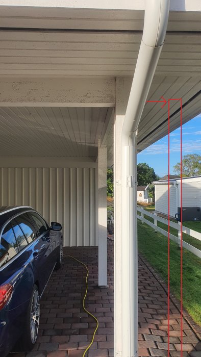 Bild på en befintlig carport med två pelare och tak som är ihopbyggt med ett hus, markerad framtida garagevägg.