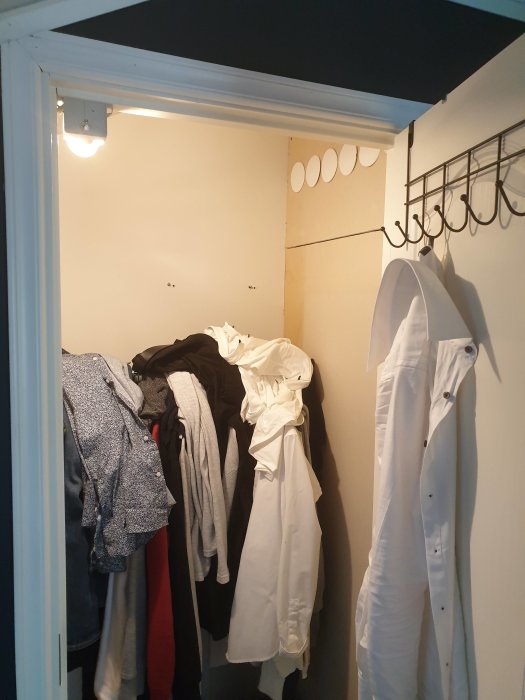 Ett litet förråd fullt med kläder och plattor på väggen som kan vara en del av ventilationssystemet.