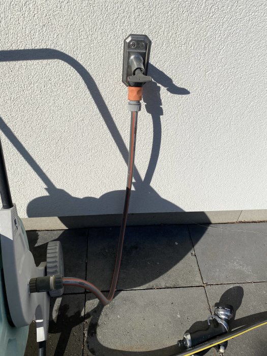 Vattenutkastare på vägg med ansluten PEM-slang på husets utsida.