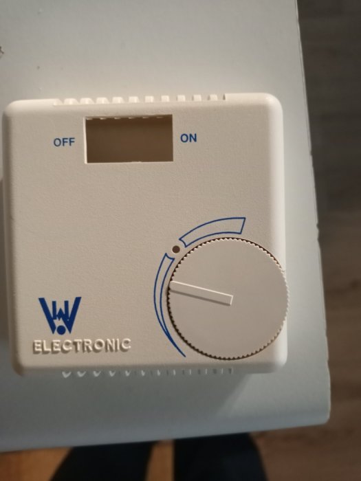 Vit termostat för golvvärme från W Electronic med på- och avställningsknapp samt temperaturvred.